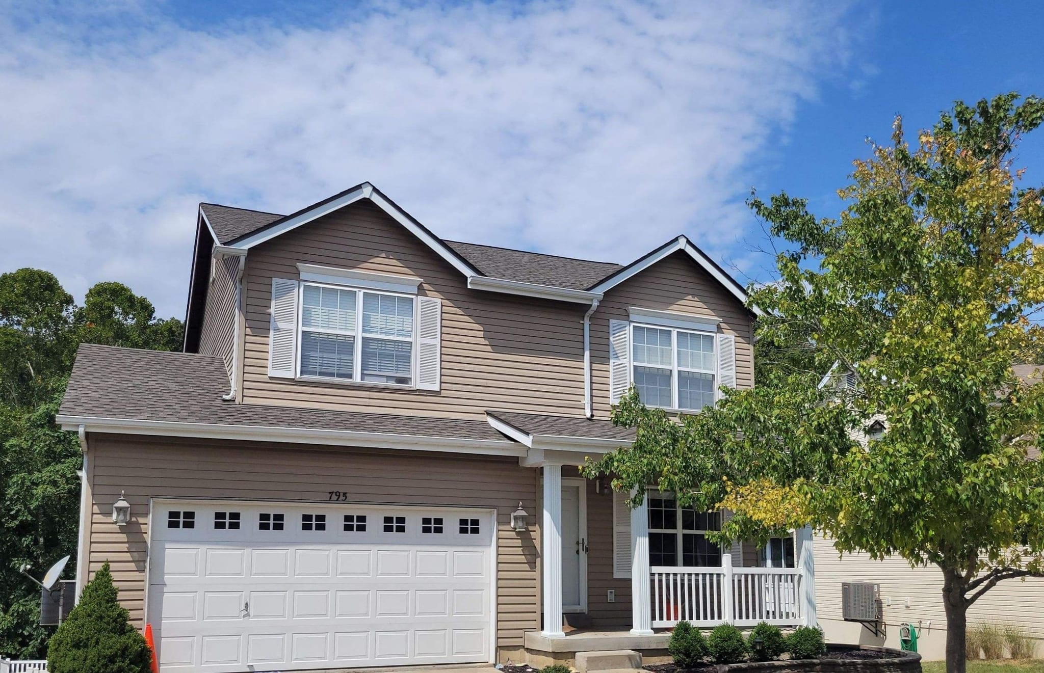 Completed brown architectural shingle roof on a two-story tan sided home with an attached two-car garage in High Ridge, MO