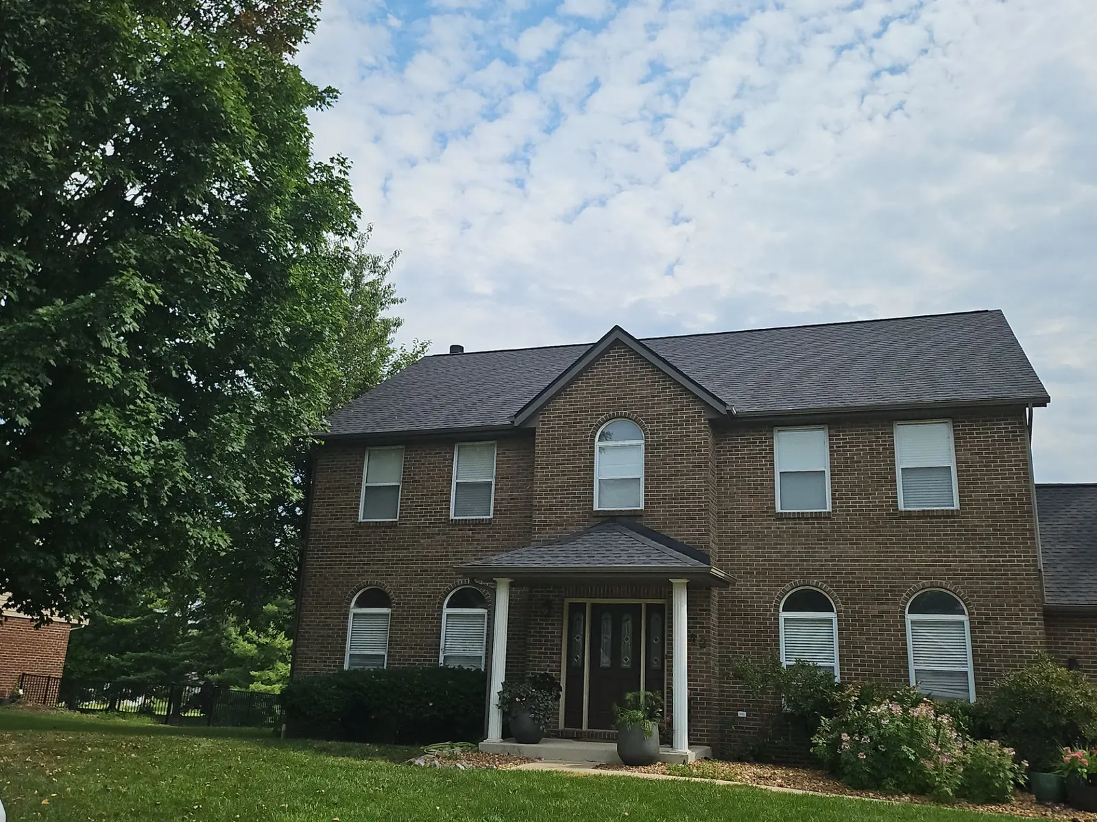 Completed dark architectural shingle roof on a two-story brick colonial home in Belleville, IL