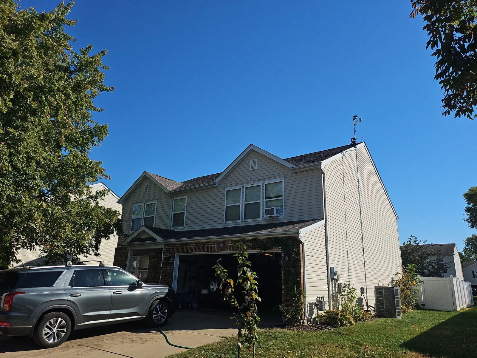 Finished architectural shingle roof on a tan-sided two-story home with a brick-front garage in Mascoutah, IL